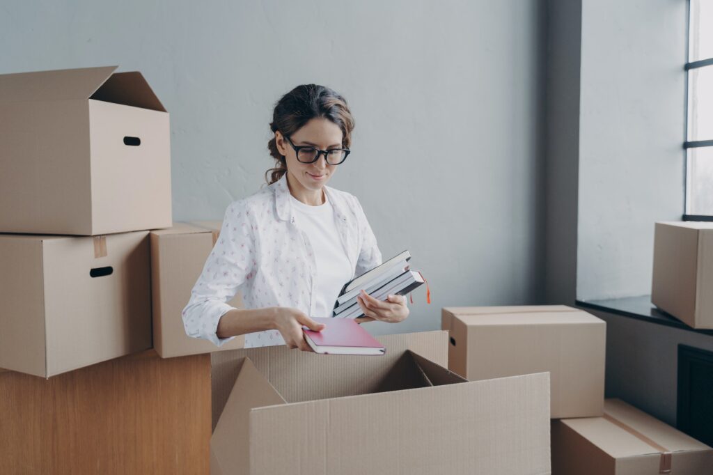 Businesswoman packs things in cardboard boxes on moving day, preparing for relocation in new office